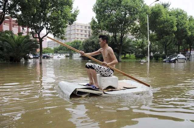 A man paddles a makeshift boat along a flooded street after heavy rainfall hit Wuhan, Hubei province, China, July 24, 2015. (Photo by Reuters/Stringer)