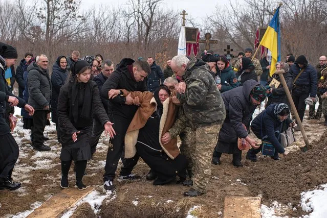 Hanna Bespalko, 54, faints after throwing soil at the coffin with her son Denys Hrynchuk, at the cemetery in Bila Krynytsia, on March 6, 2022 in Chernivtsi region, Ukraine. Denys Hrynchuk served in the Ukrainian army. He was killed on February 28, 2022, near Volnovakha, Donetsk region. He is survived by his mother, five brothers and a sister, his wife and his one-year-old son. Ukrainians from the eastern and central parts of the country have increasingly fled to western cities as Russian forces advance toward Kyiv from three sides. Russia's large-scale invasion of Ukraine has prompted widespread condemnation from European countries, coupled with sanctions on Russia and promises of military support for Ukraine. (Photo by Alexey Furman/Getty Images)