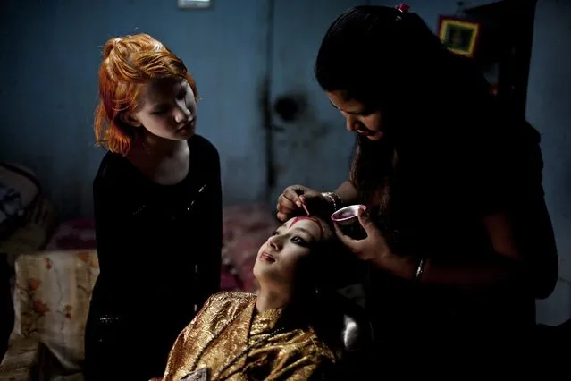 A file picture dated 24 June 2012 shows Purna Shova Bajracharya (R), mother of Kumari Samita Bajracharya (C), puting on makeup on her daughter's face for a festival procession at Kumari Ghar in Patan, Nepal. Kumari, the living goddess, appears outside of her residence during different jatras for nine times a year as a guest. Kumari, or Kumari Devi, is a “living goddess”. The word literally means virgin in Nepali. The Living Goddesses are young pre-pubescent girls that are considered to be incarnations of the Hindu Goddess of Power, Kali. The Kumari retires when she reaches puberty. (Photo by Narendra Shrestha/EPA)