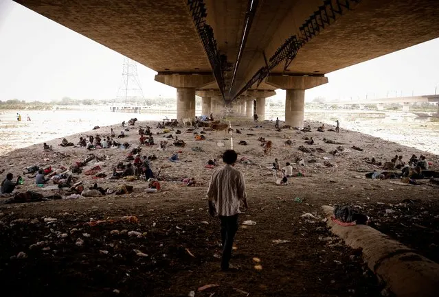 People sleep on the Yamuna river bed under a bridge on a hot summer day in New Delhi, India, May 2, 2022. (Photo by Adnan Abidi/Reuters)
