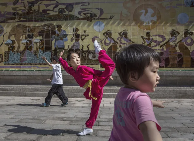 A young Chinese girl kicks during a kung-fu class at Ritan Park on June 11, 2016 in Beijing, China. Ritan, meaning “sun altar”, is among the oldest parks in Beijing, built in the early 1500s during the Ming dynasty for the emperor to make sacrifices to the sun. Less than half a kilometer square, Ritan these days is considered an oasis of green space in a sprawling city of skyscrapers, notorious air pollution, and a population of over 20 million people. Most Chinese live in small apartments with no access to gardens, leaving parks as a welcome haven for people, especially the elderly, to exercise, socialize, or enjoy a degree of privacy. (Photo by Kevin Frayer/Getty Images)