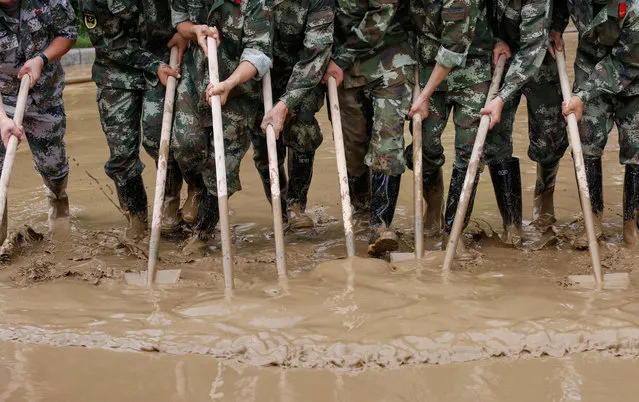 Paramilitary policemen sweep a flooded street in Guilin, Guangxi province, China on July 4, 2017. (Photo by Reuters/Stringer)
