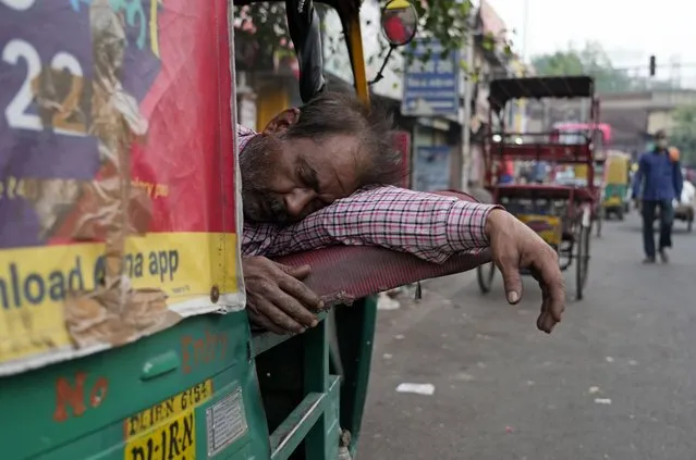 A man sleeps inside his auto rickshaw outside the railway station in New Delhi, Friday, May 27, 2022. (Photo by Rajesh Kumar Singh/AP Photo)