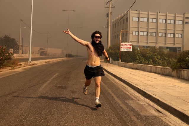 A man runs, during a wildfire in Nea Penteli near Athens, Greece, on August 12, 2024. (Photo by Costas Baltas/Anadolu via Getty Images)