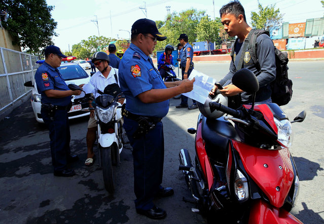 Members of the Philippine National Police inspect documents at a checkpoint on a main street of Tondo city, metro Manila, Philippines June 10, 2016. (Photo by Romeo Ranoco/Reuters)