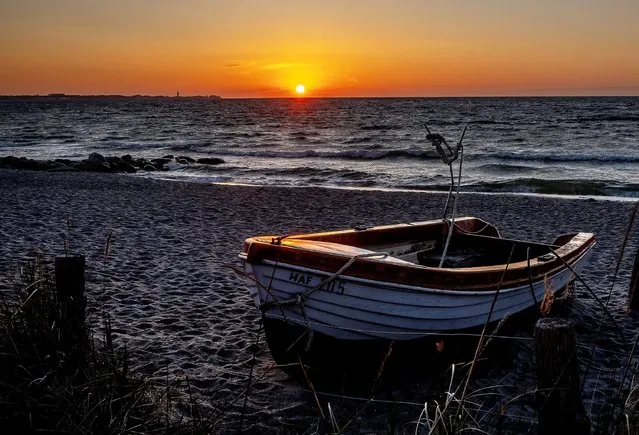 A small fisher boat lies at the beach of the Baltic Sea inn Haffkrug, Germany, as the sun rises on Friday, April 22, 2022. (Photo by Michael Probst/AP Photo)