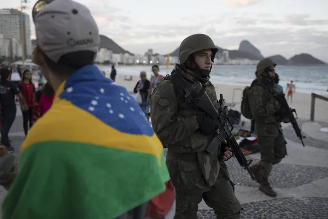 In this Sunday, July 30, 2017 photo, soldiers patrol Copacabana beach in Rio de Janeiro, Brazil. Thousands of soldiers began patrolling Rio de Janeiro amid a spike in violence in Brazil's second-largest city. (Photo by Leo Correa/AP Photo)