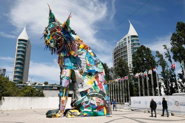 Pedestrians walk past a sculpture created by Portuguese artist Artur Bordalo aka Bordalo II in Lisbon, on June 30, 2022, as part of the UN Ocean Conference. A major UN conference on how to restore the faltering health of global oceans kicked off in Lisbon on June 27, 2022 with a flurry of promises to expand marine protected areas, ban deep-sea mining, and combat illegal fishing. (Photo by Ludovic Marin/AFP Photo)