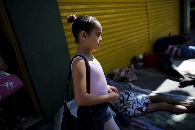 A young girl walks towards ballet lessons at the New Dreams dance studio, as people sleep on the street in the Luz neighborhood known to locals as Cracolandia (Crackland) in Sao Paulo, Brazil, August 14, 2015. (Photo by Nacho Doce/Reuters)