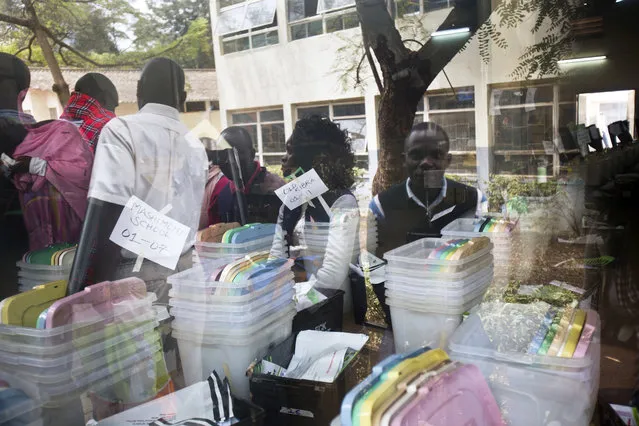 Kenyan election volunteers are reflected in the window of a room containing ballot boxes and electoral material to be distributed to various polling stations in Nairobi, Kenya, Monday, August 7, 2017. (Photo by Jerome Delay/AP Photo)