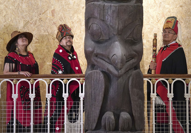 Earl Stephens, who has the Nisga'a cultural name Chief Ni'is Joohl, centre left, with Pamela Brown, left and another member of the delegation from the Nisga'a nation pose beside the 11-metre tall memorial pole,  during a visit to the National Museum of Scotland, ahead of its return to what is now British Columbia, in Edinburgh, Monday, August 28, 2023. Members of a Canadian First Nation held a spiritual ceremony on Monday at a Scottish museum to begin the homeward journey of a totem pole stolen almost a century ago.  (Photo by Andrew Milligan/PA Wire via AP Photo)