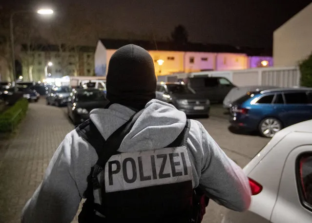 A police officer guards the road in front of a house that is searched through by police in Hanau, Germany Thursday, February 20, 2020. Eight people were killed in shootings in and outside two hookah lounges in a southwestern German city late Wednesday, and authorities were searching for the perpetrators. (Photo by Michael Probst/AP Photo)