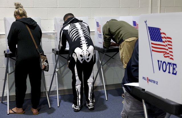 Ready for Halloween, Mark Reynolds, center,  votes early beside his wife Jennifer, left, at the St. Charles County Election Authority in St. Charles, Mo. on Thursday, October 31, 2024. (Photo by Robert Cohen/St. Louis Post-Dispatch via AP Photo)