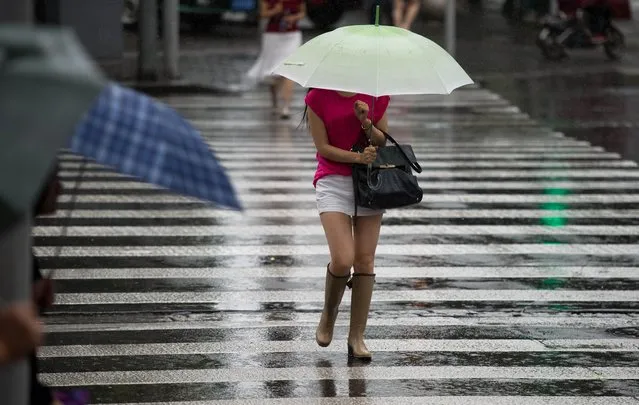 A woman holds an umbrella in the streets of Shanghai during rainfall on August 1, 2014. Chinese economic growth accelerated to a higher-than-expected 7.5 percent in the second quarter, up from 7.4 percent in the previous three months, which was the worst since a similar 7.4 percent expansion in July-September 2012. (Photo by Johannes Eisele/AFP Photo)