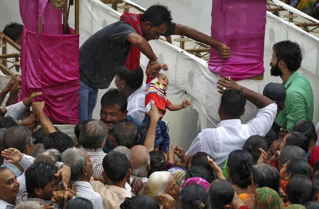 A man lifts a child as devotees arrive to receive offerings being distributed by the temple authority at Jagannath temple ahead of the annual Rath Yatra, or chariot procession, in Ahmedabad, India, July 4, 2016. (Photo by Amit Dave/Reuters)