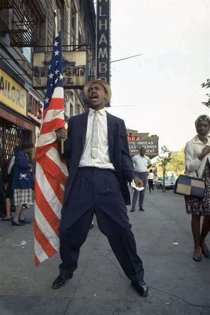 In this 1964 file photo, an unidentified black civil rights demonstrator carries a U.S. flag outside the Alhambra Theatre in Harlem neighborhood of New York. “Flags are, by their nature, emotion-charged emblems, and that's especially the case in the U.S.”, says John Hartvigsen, president of the North American Vexillological Association, a group of scholars dedicated to the study of flags. (Photo by AP Photo)