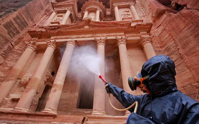 A labourer sprays disinfectant in Jordan's archaeological city of Petra south of the capital Amman on March 17, 2020, to prevent the spread of COVID-19. (Photo by Khalil Mazraawi/AFP Photo)