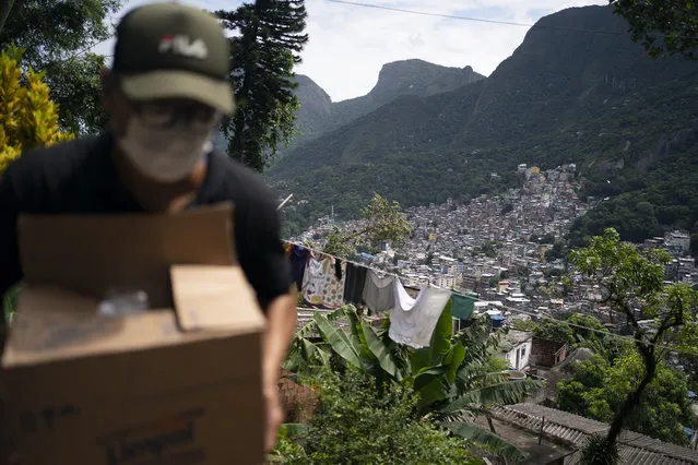 A local volunteer carries a package with soap and detergent to be distributed in an effort to stop the spread of the new coronavirus in the Rocinha slum of Rio de Janeiro, Brazil, Tuesday, March 24, 2020. (Photo by Leo Correa/AP Photo)