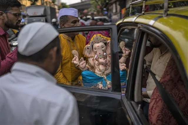 Devotees carry an idol of elephant-headed Hindu god Ganesha to take home for worship during Ganesh Chaturthi festival celebrations in Mumbai, India, Wednesday, August 31, 2022. The 10-day long Ganesh festival began Wednesday and ends with the immersion of Ganesha idols in water bodies on the final day. (Photo by Rafiq Maqbool/AP Photo)