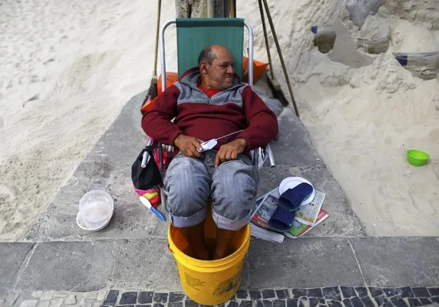 2016 Rio Olympics, Olympic Park on July 29, 2016. A man listens to the radio as he sits with his feet in a bucket of water. (Photo by Ivan Alvarado/Reuters)