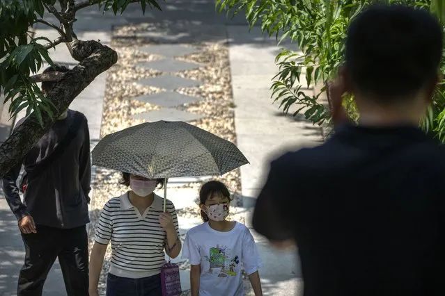 A woman and child wearing face masks walk along a path at a public park in Beijing, Tuesday, August 30, 2022. (Photo by Mark Schiefelbein/AP Photo)