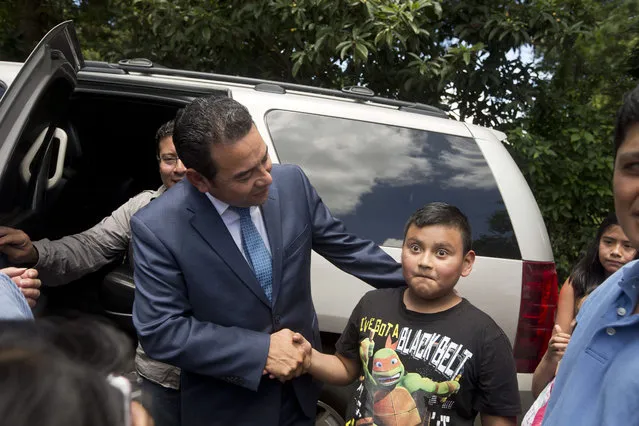 Television comedian and presidential candidate for the National Front of Convergence party Jimmy Morales shakes the hand of a boy as he leaves after voting at a polling station in Mixco, Guatemala, Sunday, September 6, 2015. (Photo by Esteban Felix/AP Photo)