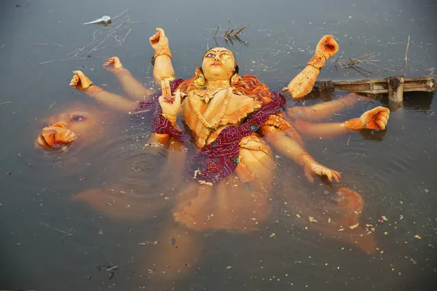 An idol of the Hindu goddess Durga floats in a temporary pond near the River Ganges after its immersion in Allahabad, India, Saturday, September 30, 2017. The immersion of idols marks the end of the festival that commemorates the slaying of a demon king by lion-riding, 10-armed goddess Durga, marking the triumph of good over evil. (Photo by Rajesh Kumar Singh/AP Photo)