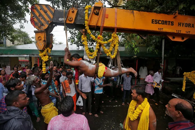 A Hindu devotee with his back and legs pierced with iron hooks suspends from a crane during an annual religious procession called Shitla Mata in Ahmedabad, India, July 23, 2017. (Photo by Amit Dave/Reuters)