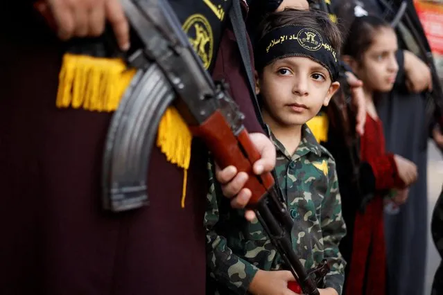 A boy looks on as Palestinian Islamic Jihad militants march in a rally marking the 35th anniversary of the movement's foundation, in Khan Younis in the southern Gaza Strip on October 4, 2022. (Photo by Ibraheem Abu Mustafa/Reuters)