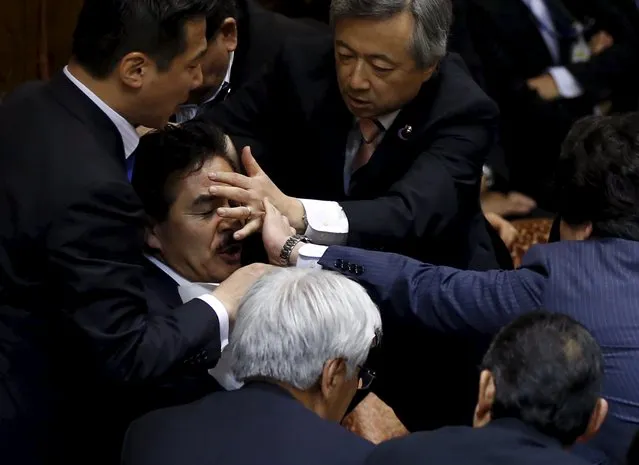 Opposition lawmakers crowd around Masahisa Sato (2nd L), deputation chairman of the upper house special committee on security, at an upper house special committee session on security-related legislation at the parliament in Tokyo, Japan, September 17, 2015. (Photo by Toru Hanai/Reuters)