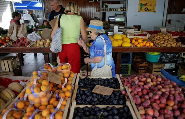 A woman buys fruit and vegetables in a street market in Rome, Italy, August 11, 2016. (Photo by Max Rossi/Reuters)