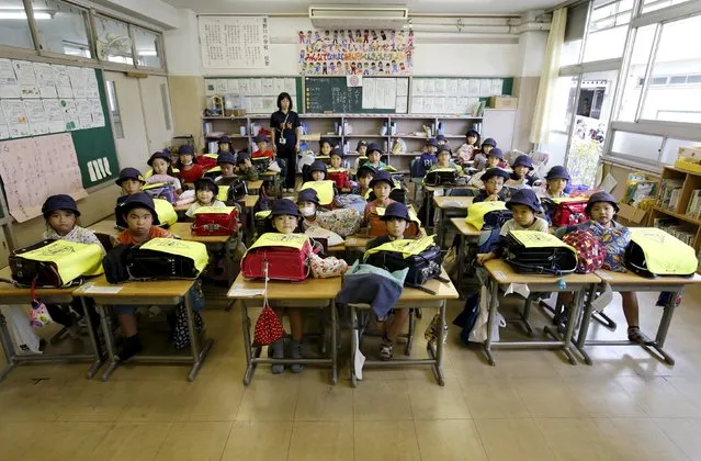 First grade students and their class teacher Teruko Takakusaki (in background) pose for a photo during their homeroom period at the end of the school day at Takinogawa Elementary School in Tokyo, Japan, September 18, 2015. (Photo by Toru Hanai/Reuters)