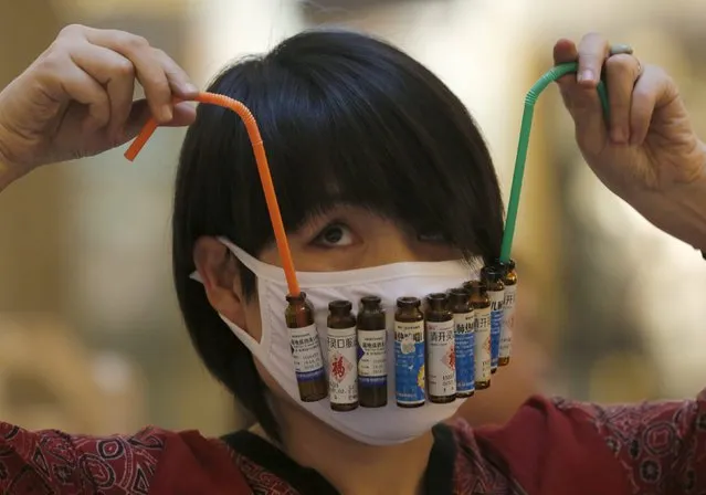 Chinese designer Wen Fang adjusts straws on her mask decorated with asthma medicine bottles at her "Maskbook" workshop during the Beijing Design Week 2015 in Beijing, China, October 2, 2015. (Photo by Kim Kyung-Hoon/Reuters)