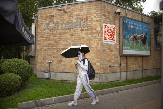 A woman wearing a face mask to help protect against the coronavirus walks past the Canadian Embassy in Beijing, Thursday, August 6, 2020. China has sentenced a Canadian citizen to death on charges of manufacturing the drug ketamine amid heightened tension between the two countries. (Photo by Mark Schiefelbein/AP Photo)