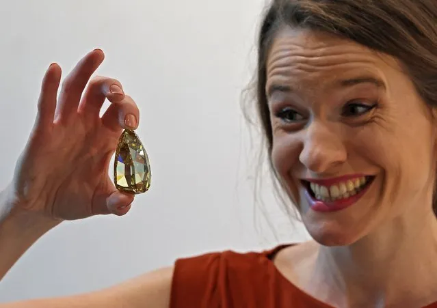 An employee holds up the “Golden Canary” brownish-yellow coloured diamond, weighing 303.10 carats, at Sotheby's in the Gulf emirate of Dubai on October 17, 2022. (Photo by Giuseppe Cacace/AFP Photo)