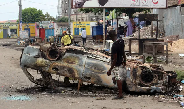 A man stands next to a burnt out car after a protest in Kinshasa, Democratic Republic of Congo, Monday, September 19, 2016. (Photo by John Bompengo/AP Photo)