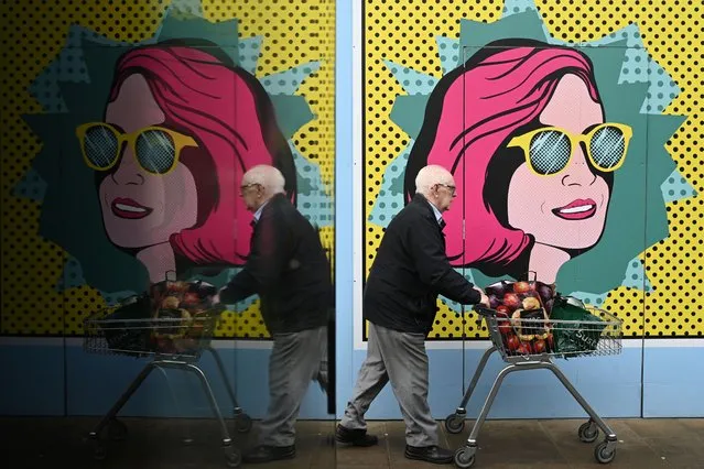 A man pushes a cart past colourful boards put up at a closed shop in Chester on November 17, 2022. Britain unveiled an austerity budget with £55 billion ($65 billion) of tax hikes and spending cuts despite confirming its economy was in recession. (Photo by Oli Scarff/AFP Photo)