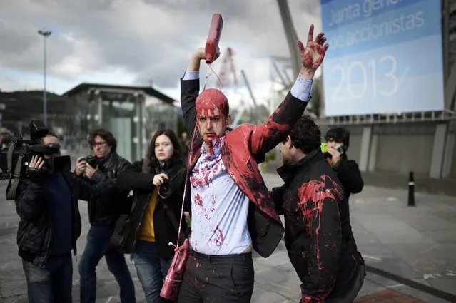 A member of the pacifist group Platform Against The BBVA covers himself in red paint to symbolise investments in armaments as he is led away by a policeman before the Annual General Meeting of Shareholders of Spain's second biggest bank BBVA, at the Palacio Euskalduna in Bilbao March 15, 2013. (Photo by Vincent West/Reuters)