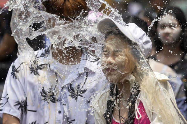 A couple react as a bucket of water is splashed on them during the Songkran water festival to celebrate the Thai New Year in Prachinburi Province, Thailand, Saturday, April 13, 2024. It's the time of year when many Southeast Asian countries hold nationwide water festivals to beat the seasonal heat, as celebrants splash friends, family and strangers alike in often raucous celebration to mark the traditional Theravada Buddhist New Year. (Photo by Wason Wanichakorn/AP Photo)