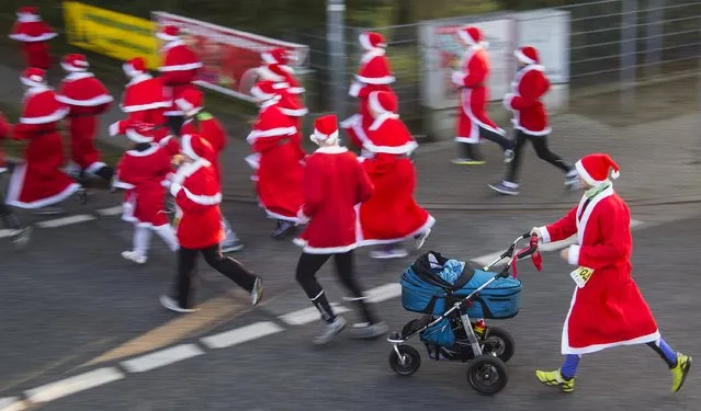 A runner dressed as Father Christmas pushes a baby stroller during the Nikolaus Lauf (Santa Claus Run) in the east German town of Michendorf, southwest of Berlin December 7, 2014. (Photo by Hannibal Hanschke/Reuters)