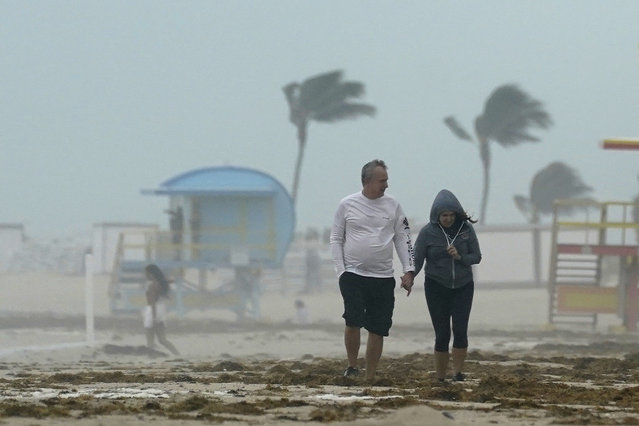 A couple walks along the beach during a downpour, Sunday, November 8, 2020, on Miami Beach, Florida's famed South Beach. A strengthening Tropical Storm Eta cut across Cuba on Sunday, and forecasters say it's likely to be a hurricane before hitting the Florida Keys Sunday night or Monday. (Photo by Wilfredo Lee/AP Photo)