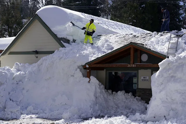 A worker clears snow off the roof of Skyforest Elks Lodge after a series of storms, Wednesday, March 8, 2023, in Rimforest, Calif. (Photo by Marcio Jose Sanchez/AP Photo)