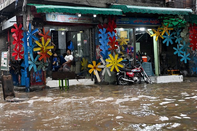 Shopkeepers sit inside their store, amid a flooded road during heavy rain in Lahore on August 30, 2025. Monsoon rains this week swelled three transboundary rivers that cut through Pakistan's eastern province, the nation's agricultural heartland and home to nearly half of its 255 million people. (Photo by Aamir Qureshi/AFP Photo)