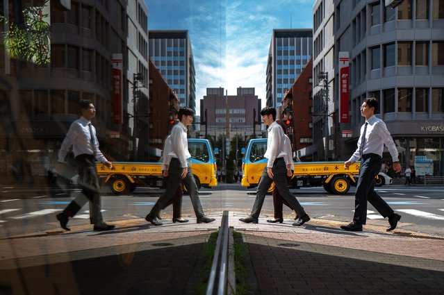 Pedestrians are seen reflected in glass as they walk in the Ginza district of Tokyo on October 8, 2025. (Photo by Philip Fong/AFP Photo)