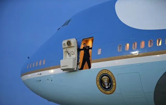 A crew member stands in the door of Air Force One waiting for the passenger stairs, upon the arrival of U.S. President Barack Obama at Joint Base Andrews in Washington January 8, 2015. Obama returned from a two-day trip to Michigan and Arizona. (Photo by Kevin Lamarque/Reuters)