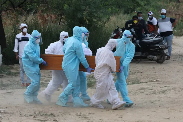 Relatives wearing personal protective equipment carry a coffin into a grave during a funeral service of a Covid-19 victim at designated area only for coronavirus funerals at the burial site in New Delhi, India, 16 June 2020 (issued 02 July 2020). India has registered more than 17,000 deaths and over 590,000 cases of coronavirus. The caseload surged significantly after a two and a half month lockdown was lifted in early June, causing a major overload in Delhi's hospitals. (Photo by Harish Tyagi/EPA/EFE)