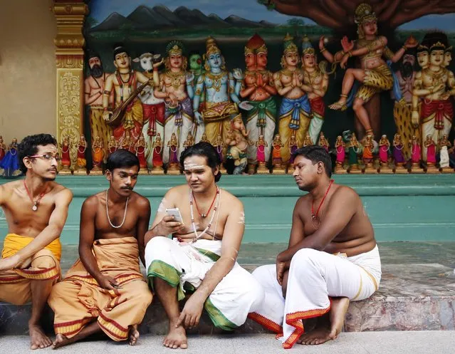 Hindu holy men check a mobile phone as they wait for devotees on the first day of the Pongal festival at a temple in Kuala Lumpur January 14, 2015. (Photo by Olivia Harris/Reuters)
