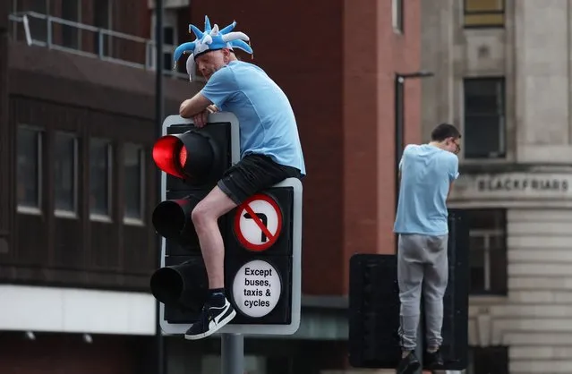 Manchester City fans seen climbing traffic lights ahead of the parade in Manchester, Britain on June 12, 2023. (Photo by Phil Noble/Reuters)
