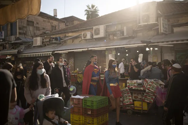 A couple wears Superman and Supergirl costumes for the Jewish holiday of Purim, as they stroll through the Mahane Yehuda Market in Jerusalem, Friday, February 26, 2021. Israel has instituted a nightly curfew during the holiday to curb the spread of the coronavirus. (Photo by Maya Alleruzzo/AP Photo)