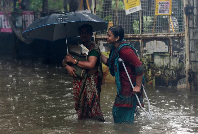 People wade through a waterlogged street during heavy rains in Mumbai, India, July 10, 2018. (Photo by Francis Mascarenhas/Reuters)